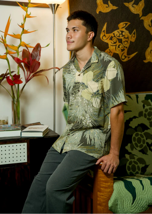 Man wearing a patterned shirt sitting in a room with decorative elements.